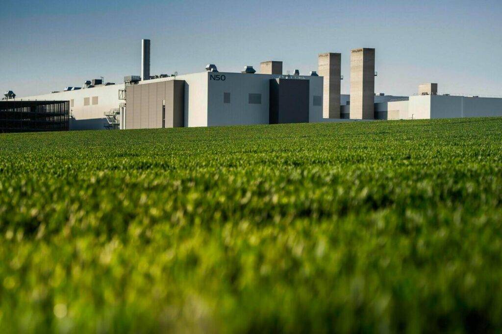 No 2024. gada 1. janvāra Audi Ingolštates rūpnīca uzsāks oglekļa neitrālu ražošanu. Nākamgad tur ceļu pie klientiem uzsāks jaunie Audi Q6 e-tron saimes modeļi. Audi vides aizsardzības programma Mission:Zero paredz, ka klimatneitrāla  ražošana 2025. gadā tiks panākta visās uzņēmuma rūpnīcās. Jau 2018. gadā šis mērķis ir sasniegts Audi Q8 e-tron ražotnē Briselē, Beļģijā, bet 2020. gadā Audi Ģēras ražotnē Ungārijā. Tur top Latvijā pieprasītie Audi Q3. Kopš 2020. gada klimatneitrāla ražošana tiek nodrošināta arī sportiskajiem Audi R8 un Audi e-tron GT modeļiem Böllinger Höfe rūpnīcā Vācijā.

Audi par ražošanas un loģistikas jautājumiem atbildīgais valdes loceklis Gerds Valkers (Gerd Walker) uzsver: “Vides aizsardzība ir viens no Audi korporatīvās stratēģijas stūrakmeņiem. Ingolštates rūpnīcā, uzsākot atjaunīgas enerģijas izmantošanu, ir sperts nozīmīgs solis ceļā uz oglekļa izmešu neitrālu automobiļu ražošanu.” Lai šo ambiciozo mērķi sasniegtu, Audi īsteno četru principu konceptu.

Pirmais princips paredz energoefektivitātes uzlabošanu Audi rūpnīcās, kas jau tagad ļauj ievērojami samazināt oglekļa emisiju apjomu. Piemēram, 2022. gadā šie energopārvaldības pasākumi ļāva Ingolštates rūpnīcā ietaupīt vairāk nekā 35 000 megavatstundu enerģijas un novērst vairāk nekā 5 000 tonnu oglekļa emisiju nonākšanu vidē.

Tāpat arī Audi ražo atjaunīgo enerģiju, kas ir šī koncepta otrais princips. Līdz šim Ingolštates rūpnīcā 23 000 kvadrātmetru platībā uzstādīti fotoelektriskie moduļi. Turpmākajos gados Audi turpinās palielināt pašu saražotās enerģijas īpatsvaru visās uzņēmuma rūpnīcās. Lai turpinātu šo attīstības virzienu, pašlaik galvenajā rūpnīcā tiek plānoti un īstenoti dažādi papildu pasākumi.

Trešais koncepta princips ir Audi enerģijas iepirkšana no oglekļa ziņā neitrāliem enerģijas piegādātājiem. Kopš 2012. gada sākuma Audi ražo automobiļus Ingolštatē, izmantojot tikai “zaļo” elektroenerģiju. Šī agrīnā pāreja ļāva zīmolam kļūt par ilgtspējas pionieri šajā nozarē.

Ilgtspējīga apkure

Audi Group vides aizsardzības nodaļas vadītājs Dr. Rīdigers Reknāgels (Dr. Rüdiger Recknagel) skaidro: “Netālu esošā naftas pārstrādes rūpnīca un sadzīves atkritumu pārstrādes rūpnīca apgādā galveno Audi ražotni ar oglekļa izmešu ziņā neitrālu atlikumsiltumu. Turklāt mēs esam nodrošinājuši lielu daudzumu biogāzes, lai nodrošinātu oglekļa izmešu neitrālu siltumapgādi.”

Šādā veidā rūpnīca gandrīz visu nepieciešamo enerģiju iegūst no atjaunīgajiem resursiem. Ceturtais un pēdējais princips ir – visas emisijas, no kurām Audi vēl nespēj izvairīties (ne vairāk kā 10% no sākotnējām oglekļa emisijām), tiek kompensētas, iegādājoties oglekļa kredītus, kas ir sertificēti saskaņā ar augstākajiem kvalitātes standartiem, piemēram, Zelta standartu. Ingolštates rūpnīcā tas ietver arī loģistiku rūpnīcā.

Mission:Zero: vairāk nekā emisiju samazināšana

Vides aizsardzības programmas Mission:Zero pasākumi sniedzas tālāk par dekarbonizāciju un attiecas uz galvenajām darbības jomām – ūdens izmantošanu, resursu efektivitāti un bioloģiskās daudzveidības aizsardzību un saglabāšanu. Audi vīzija ir izveidot aprites ekonomiku, kurā tādi resursi kā plastmasa, ūdens un citas izejvielas tiek izmantoti slēgtos ciklos. Piemēram, kopš 2019. gada Audi Ingolštatē izmanto tehniskā ūdens piegādes centru ar membrānu bioreaktoru, lai efektīvāk izmantotu ūdeni. Šogad Audi kļuva par pirmo premium klases automobiļu ražotāju, kas pievienojās Ūdens pārvaldības aliansei (Alliance for Water Stewardship – AWS). Audi plāno līdz 2035. gadam uz pusi samazināt ekoloģiski svērto ūdens patēriņu savās rūpnīcās visā pasaulē. Kā paraugs atbildīgai ūdens resursu izmantošanai uzskatāma rūpnīca Sanhosē Čiapā, Meksikā, kas kopš 2018. gada ražo automobiļus, neradot nekādus notekūdeņus.

Visbeidzot, kā Biodiversity in Good Company (Bioloģiskā daudzveidība labā uzņēmumā) iniciatīvas dalībnieks, Audi ir arī apņēmies visās savās rūpnīcās aizsargāt bioloģisko daudzveidību. Apkārtne pie Minhsminsteres rūpnīcas ēkām ir veidota tā, lai tā saglabātu savu dabisko vidi un formu. Aptuveni 17 hektāru platībā ir izveidota īpaša vide daudzām dzīvnieku un augu sugām.

360factory un ilgtspējīga zemes izmantošana
Ar pieeju, ko Audi dēvē par 360factory, ražotājs arī nākotnē pievērsīs lielu uzmanību rūpnīcu ilgtspējas attīstībai. Šīs visaptverošās, ilgtspējīgās pieejas ietvaros Audi modernizē, digitalizē un pārveido savas esošās rūpnīcas, lai tās būtu gatavas nākotnei un e-mobilitātei. Ar 360factory programmu Audi var panākt vēl lielāku ražošanas elastību un efektivitāti, neaizņemot papildu teritorijas jaunu ēku celtniecībai.

Tiecoties pēc ilgtspējīgas zemes izmantošanas, Audi ir spēris vēl vienu soli uz priekšu, atdzīvinot bijušo rūpniecisko teritoriju. Tehnoloģiju parks Ingolštates dienvidos arī ir integrēts uzņēmuma ilgtspējības pasākumos kā galvenās ražotnes struktūrvienība. AUDI AG un Ingolštates pilsētas kopuzņēmums incampus GmbH ir pārveidojis 75 hektāru lielu pamestu rūpniecisko teritoriju Ingolštates austrumos. Tur tika uzbūvēts tehnoloģiju parks, neattīstot jaunus zemes gabalus. Piecpadsmit hektāri no kopējās platības tika noteikti kā dabas un ainavas kompensējama teritorija – tagad tur ir aluviāls jeb dabisks mežs un pļava, kas nav ar barības vielām bagātīga.

Papildu informācija:
Kristaps Menniks 
Audi Mārketinga un sabiedrisko attiecību vadītājs Latvijā un Lietuvā
Volkswagen sabiedrisko attiecību vadītājs Baltijas valstīs
Mobilais: +371 26132172
E-pasts: Kristaps.Menniks@moller.lv
www.audi.lv

Par Audi
Audi Group ir viens no visveiksmīgākajiem premium un luksusa klases automobiļu un motociklu ražotājiem. Audi, Ducati, Lamborghini un Bentley zīmolu produkti tiek ražoti 21 rūpnīcā 13 pasaules valstīs. Audi zīmols un tā partneri ir pārstāvēti 100 pasaules valstīs.
2022. gadā Audi Group piegādāja saviem klientiem aptuveni 1,61 miljonu Audi automobiļu, 15,174 Bentley automobiļus, 9,233 Lamborghini automobiļus un 61,562 Ducati motociklus. 2021. finanšu gadā AUDI AG kopējie ieņēmumi veidoja 61,8 miljardus eiro, bet operatīvā peļņa pirms atskaitījumiem – 7,6 miljardus eiro. Audi Group visā pasaulē nodarbina vairāk nekā 87 000 cilvēku, no kuriem aptuveni 54 000 strādā Vācijā. Grupas mērķis ir būt ilgtspējīgas, individuālas un augstvērtīgas mobilitātes nodrošinātājam, piedāvājot pievilcīgus zīmolus, jaunus modeļus, mobilitātes inovācijas un progresīvus pakalpojumus.
Par Møller Baltic Import
Møller Baltic Import SE ir Møller Mobility Group AS pilnībā piederošs vairmutirdzniecības uzņēmums, kas ir Audi automašīnu importētājs Latvijā un Lietuvā, kā arī Volkswagen automašīnu importētājs Baltijas valstīs. Møller Baltic Import apgrozījums 2022. gadā bija 287 miljoni eiro, peļņa – 14 miljoni eiro.

